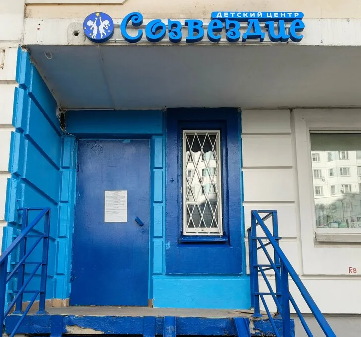 Вход в детский центр: синяя дверь и лестница, над ними вывеска «Созвездие. Детский центр»